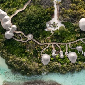 Aerial view of a resort with dome-shaped structures connected by a network of walkways. The resort is nestled within lush green foliage on an island surrounded by turquoise waters. As part of Soneva Exclusive Offers, the paths and buildings are organically integrated into the natural environment.